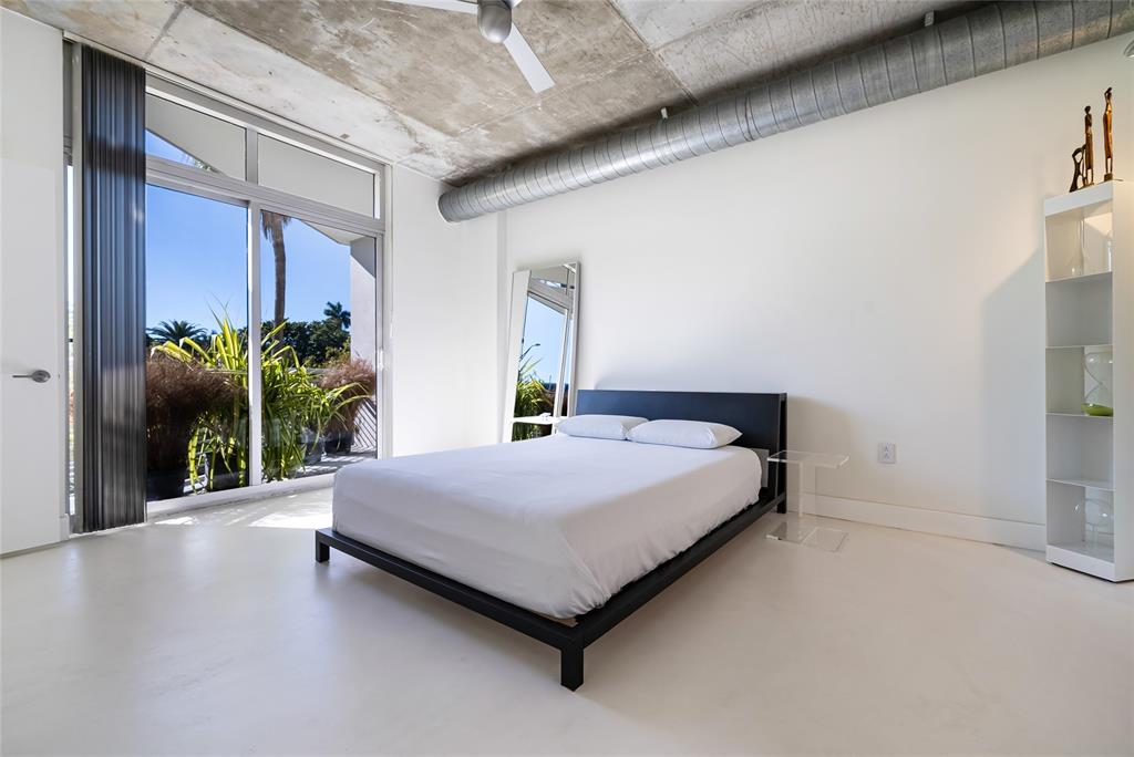 2001 Meridian Avenue, Unit 318 Miami Beach, FL 33139 - Photo 17 of 37 a bedroom with a bed and potted plants with wooden floor