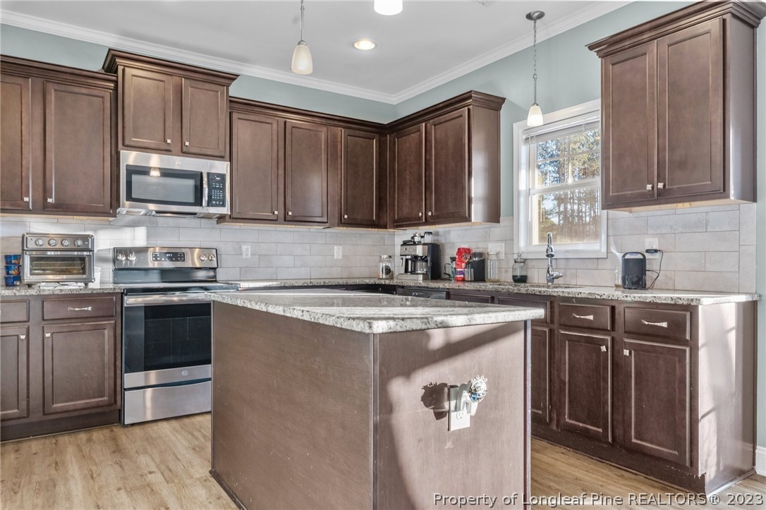 108 Roy's Ridge Raeford, NC 28376 - Photo 13 of 32 a kitchen with stainless steel appliances granite countertop a stove a sink dishwasher and a microwave oven with wooden cabinets