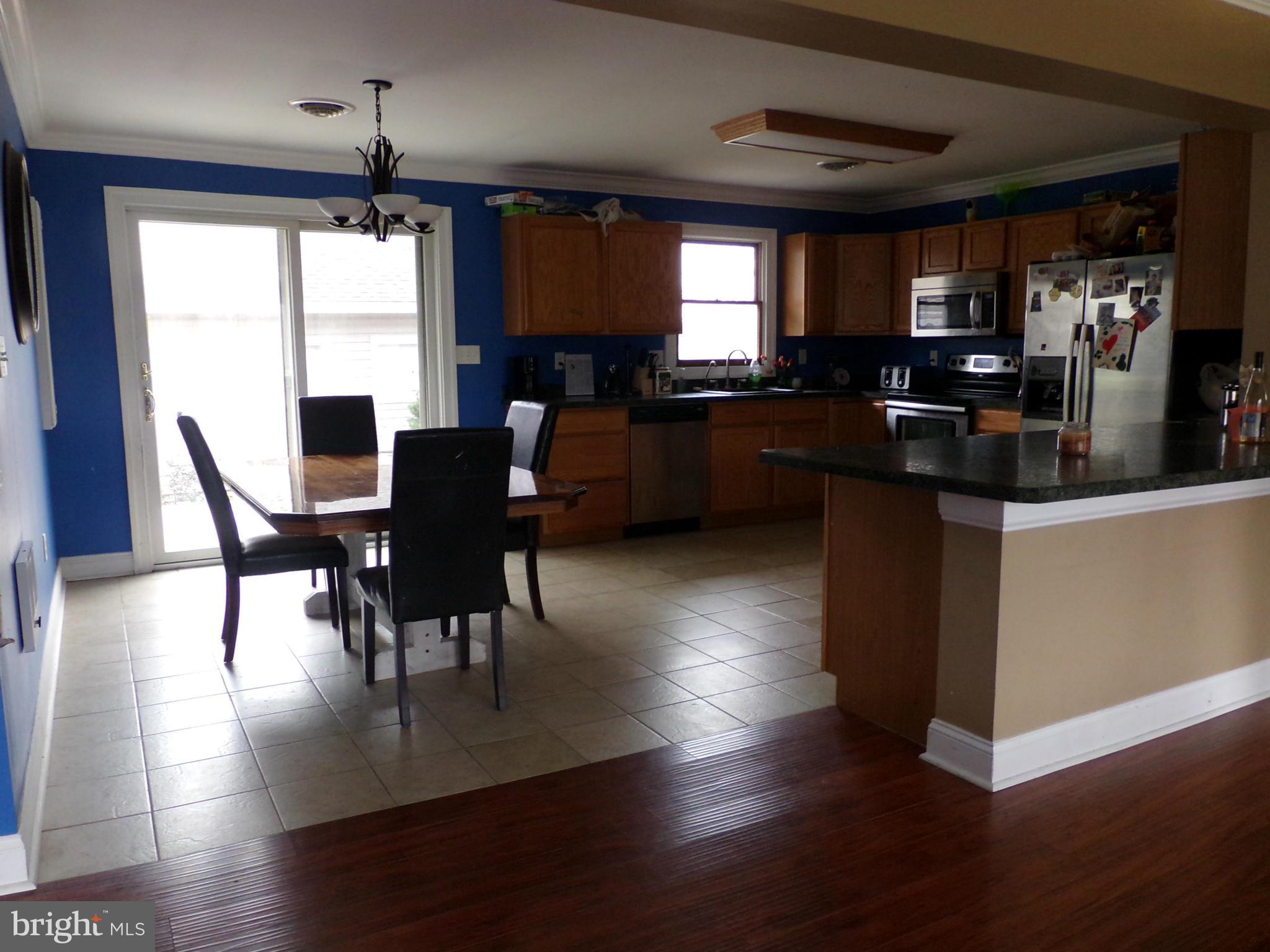 29012 Rabbit Hill Road Easton, MD 21601 - Photo 11 of 22 a kitchen with stainless steel appliances granite countertop a stove top oven a sink a dining table and chairs with wooden floor
