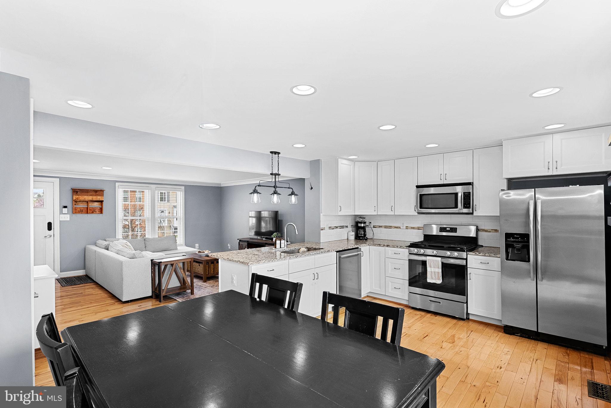 43983 Choptank Terrace Ashburn, VA 20147 - Photo 14 of 43 a large kitchen with a table chairs stainless steel appliances and wooden floor