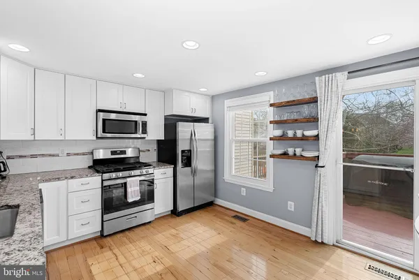 a kitchen with stainless steel appliances granite countertop a refrigerator a stove top oven and white cabinets