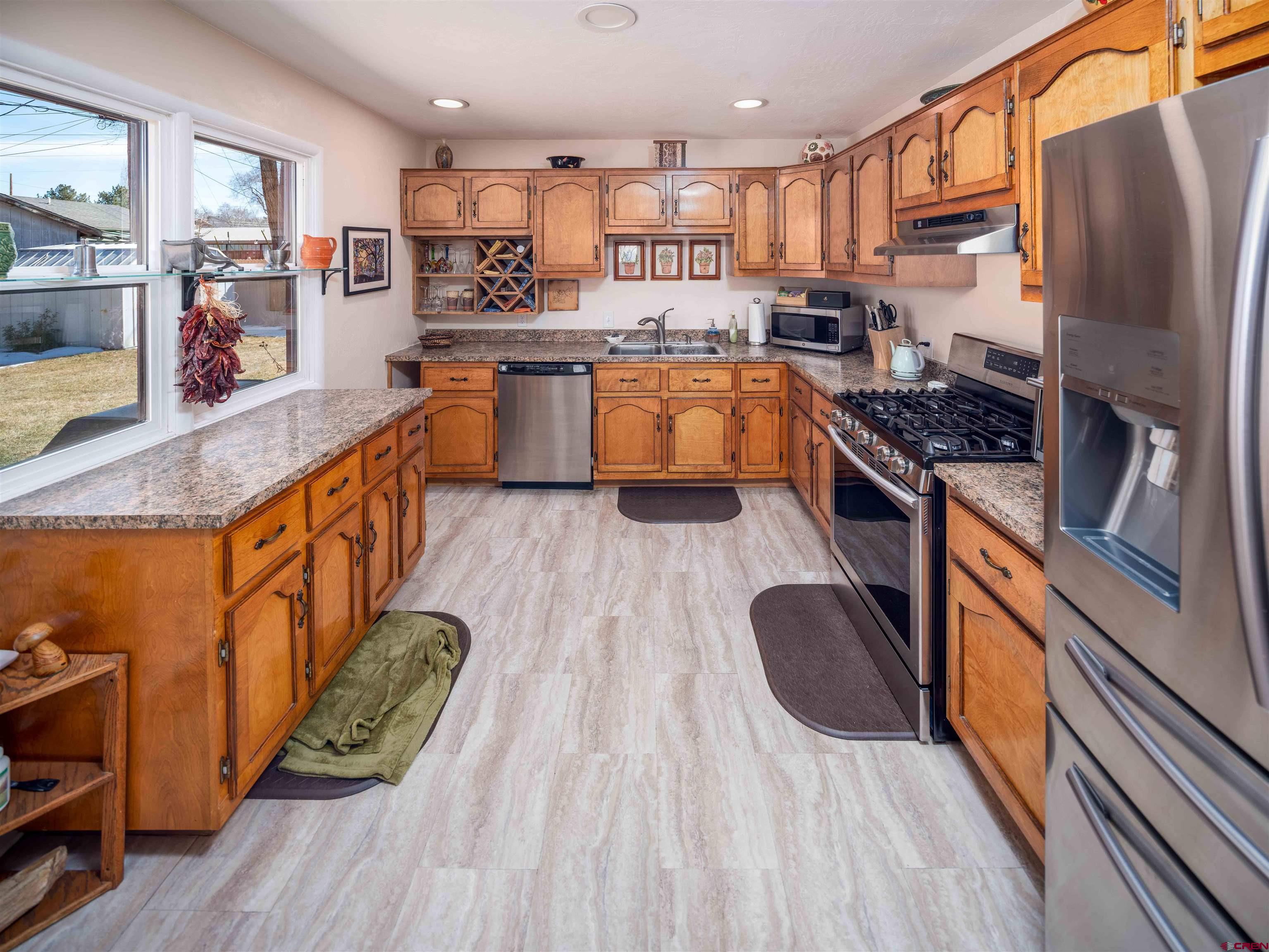 710 Wedgewood Street Cortez, CO 81321 - Photo 12 of 30 a kitchen with stainless steel appliances granite countertop a refrigerator a stove top oven and a sink with wooden floor
