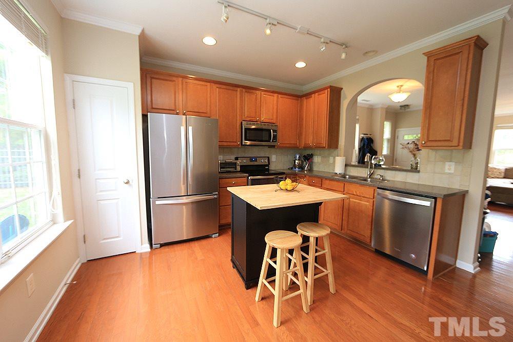 3715 Ramblewood Avenue Durham, NC 27713 - Photo 11 of 22 a kitchen with stainless steel appliances a sink a stove a refrigerator with wooden floor and cabinets