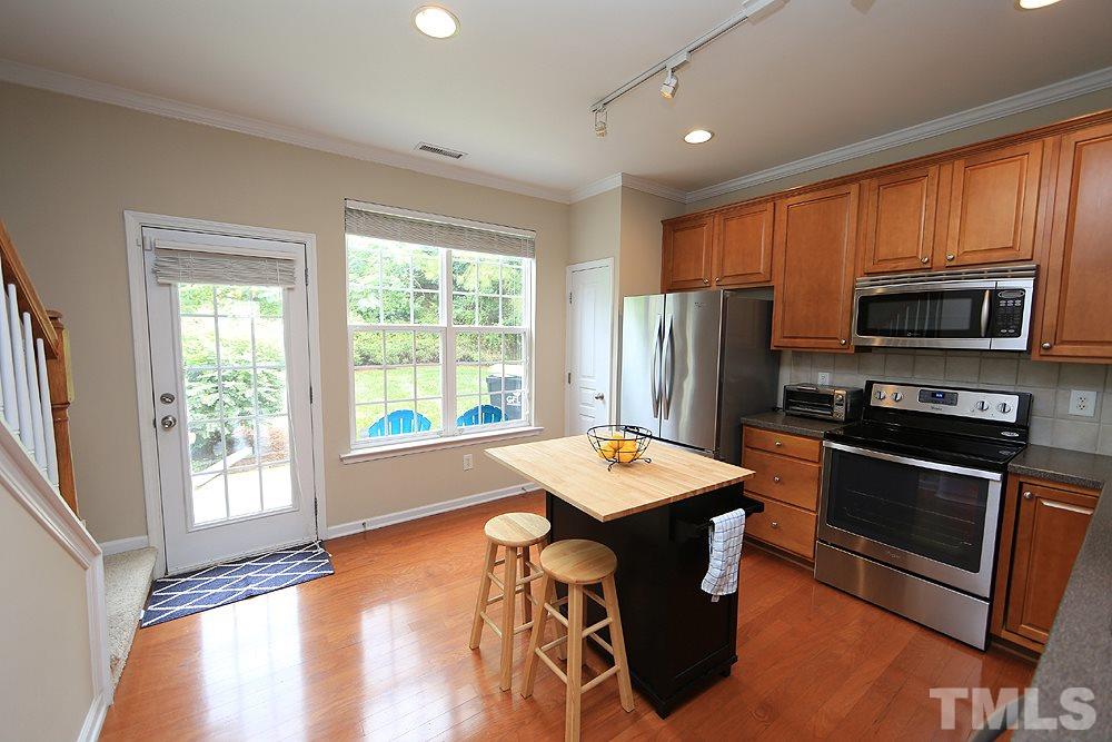 3715 Ramblewood Avenue Durham, NC 27713 - Photo 12 of 22 a kitchen island with stainless steel appliances a stove a refrigerator a sink and a microwave