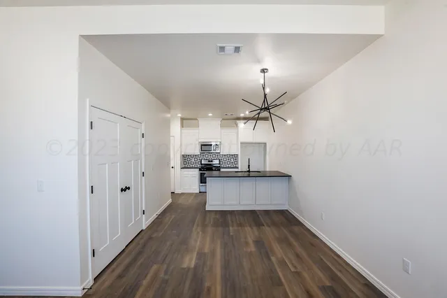 an empty room with wooden floor a ceiling fan and windows