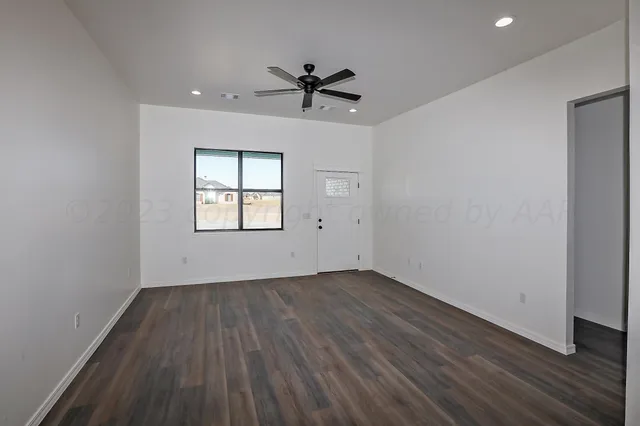 an empty room with wooden floor ceiling fan and windows