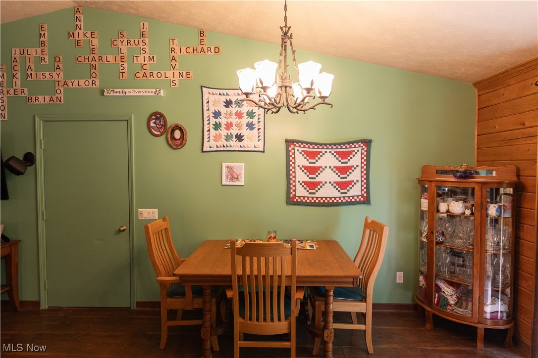 7946 Kennard Road Lodi, OH 44254 - Photo 14 of 20 Dining room featuring a textured ceiling, lofted ceiling, a chandelier, and dark hardwood / wood-style floors