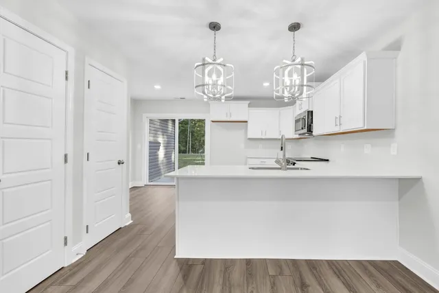 a view of a kitchen with wooden floor and stainless steel appliances