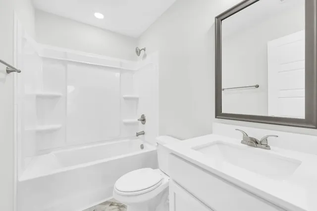 a bathroom with a bathtub shower sink vanity mirror and toilet