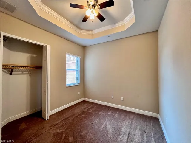 an empty room with ceiling fan and windows