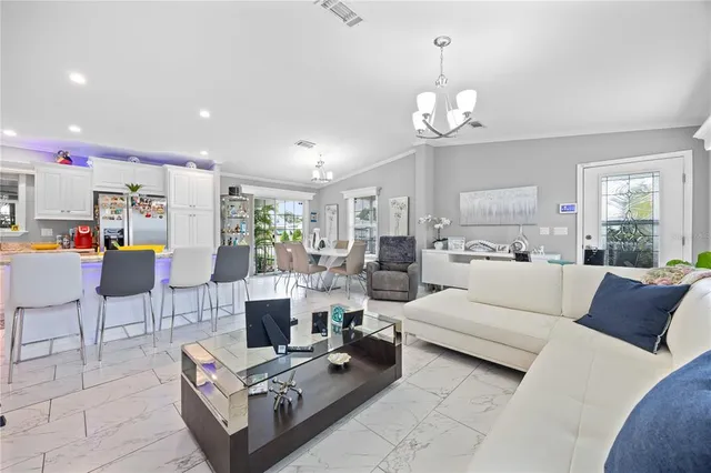 a living room with furniture a dining table and a chandelier