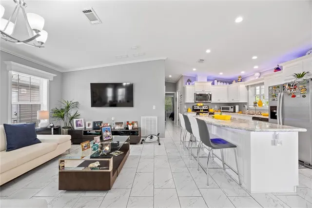 a living room with furniture kitchen view and a chandelier