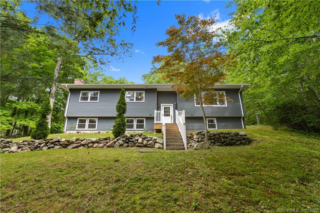 a view of a house with a big yard and large trees