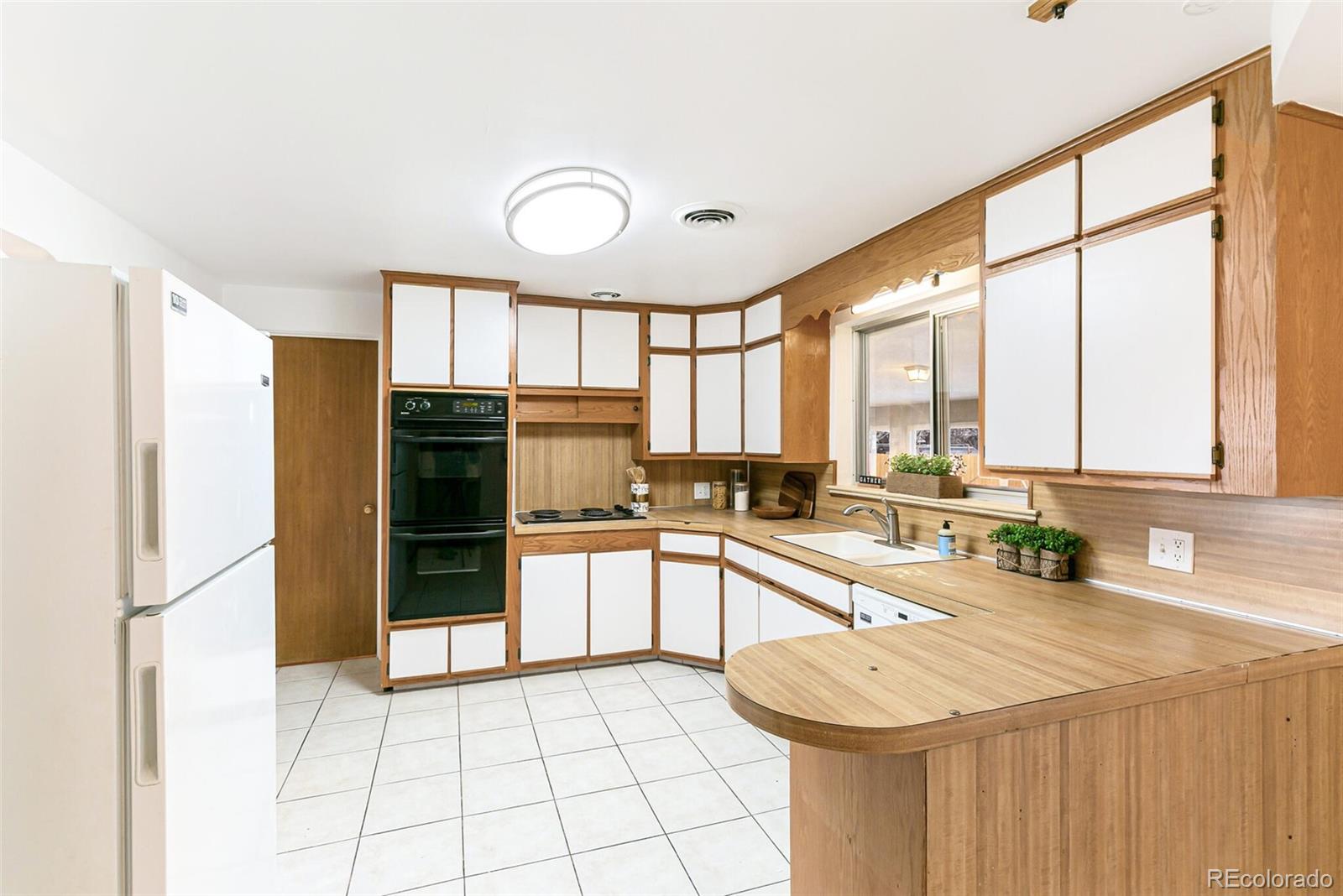 4650 Reed Street Wheat Ridge, CO 80033 - Photo 11 of 40 a kitchen with stainless steel appliances granite countertop a refrigerator a sink a stove and white cabinets with wooden floor