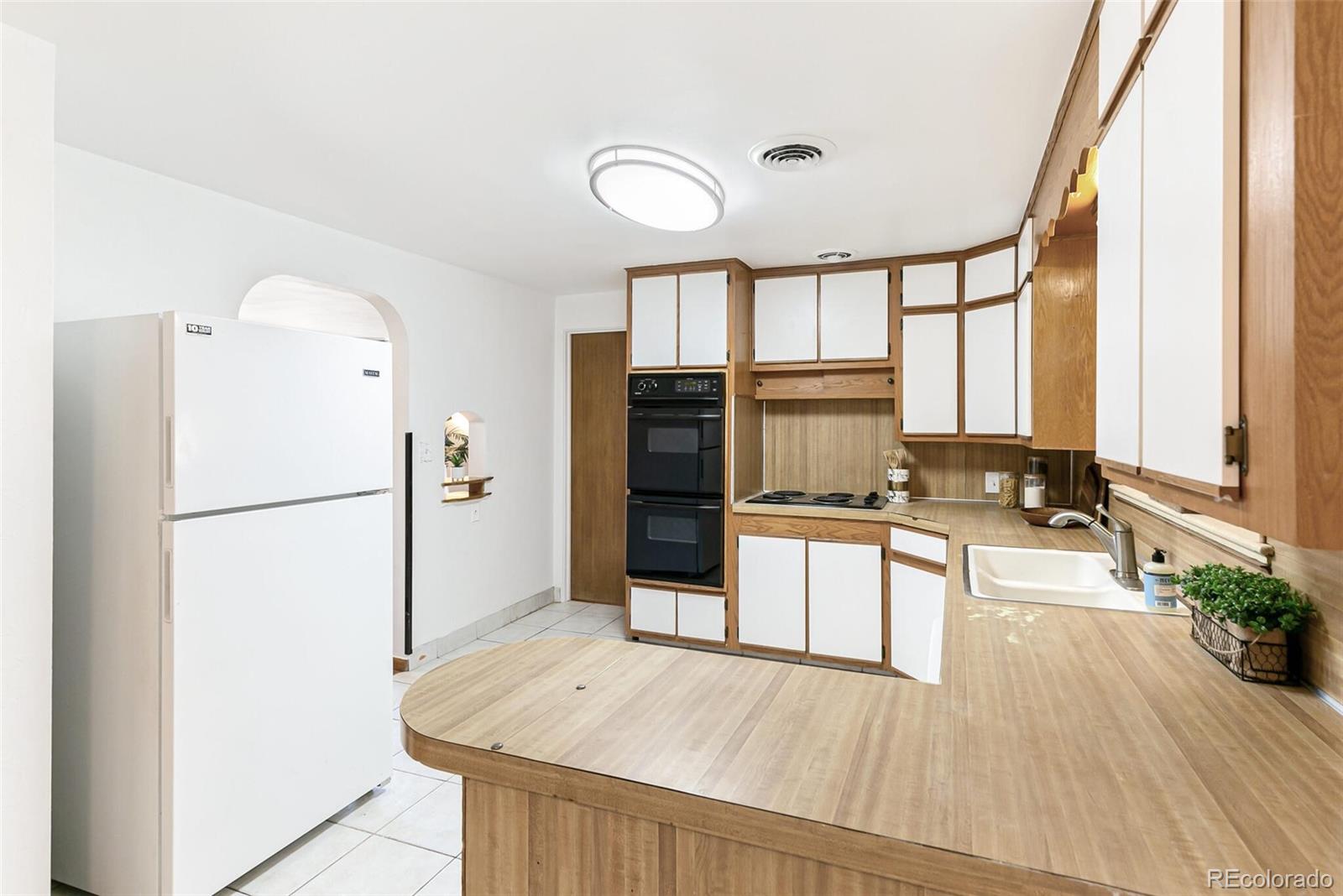4650 Reed Street Wheat Ridge, CO 80033 - Photo 10 of 40 a kitchen with stainless steel appliances a refrigerator and wooden floor
