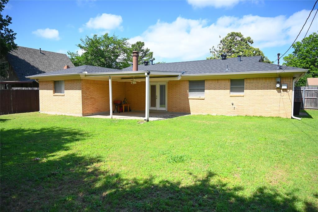 1352 Simpson Drive Hurst, TX 76053 - Photo 7 of 40 Expansive backyard featuring a covered patio with a ceiling fan, brick exterior, and a shingle roof