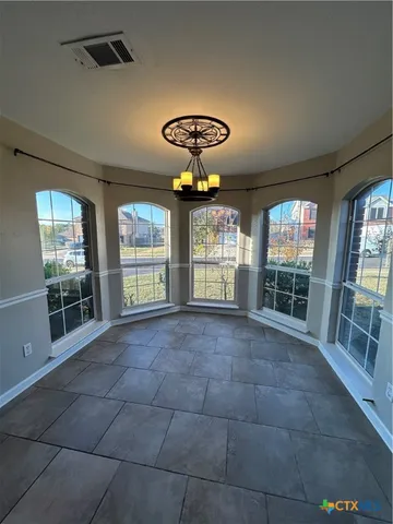 a view of an empty room with windows and chandelier
