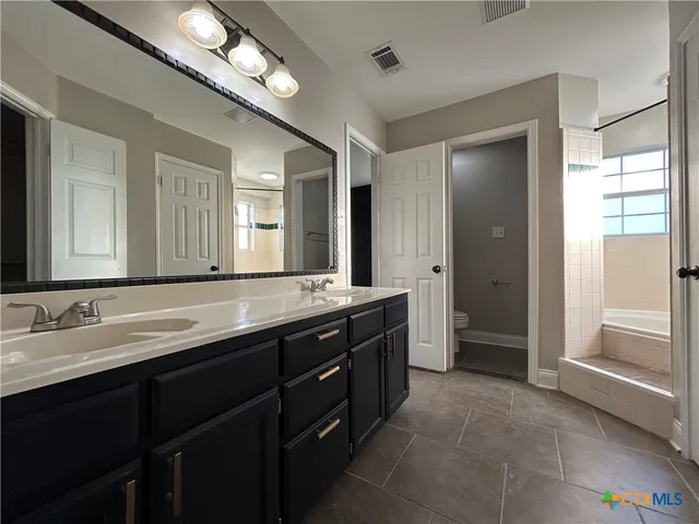 a spacious bathroom with a double vanity sink a large mirror and a shower