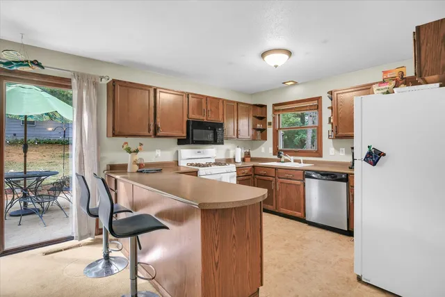 a kitchen with stainless steel appliances granite countertop a refrigerator a sink dishwasher a stove and white cabinets with wooden floor