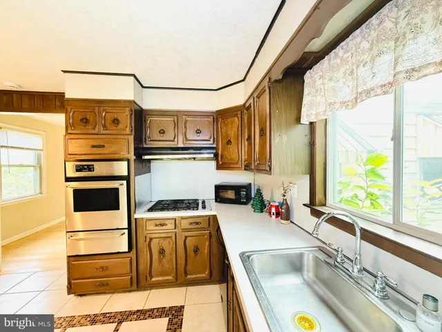 a kitchen with stainless steel appliances granite countertop a sink and a stove next to a window