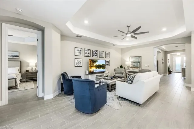 a living room with couches and kitchen view with wooden floor
