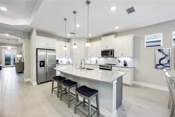 a kitchen with stainless steel appliances kitchen island a refrigerator a stove a microwave oven a sink with island and chairs