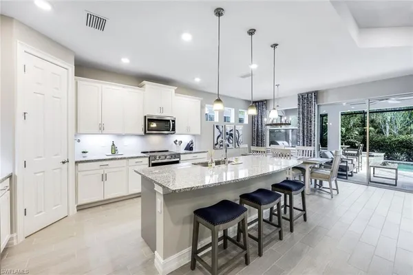a large kitchen with cabinets chairs a sink and appliances