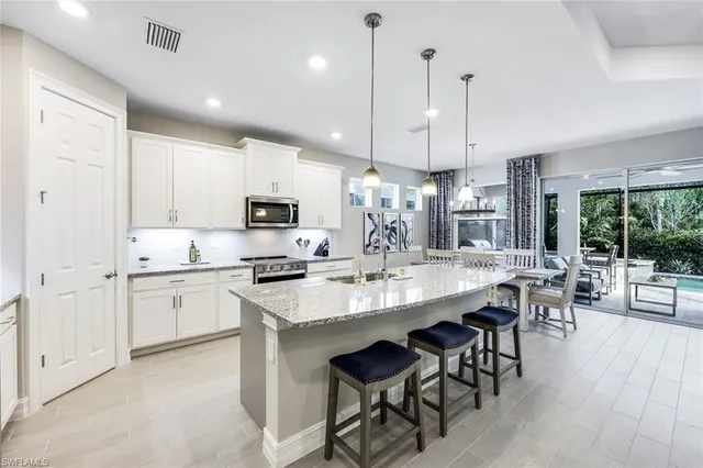 a large kitchen with cabinets chairs a sink and appliances