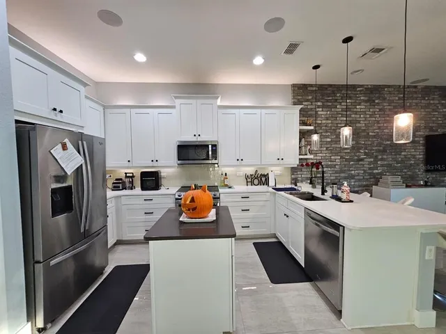 a kitchen with stainless steel appliances granite countertop a refrigerator a stove a sink dishwasher and white cabinets with wooden floor