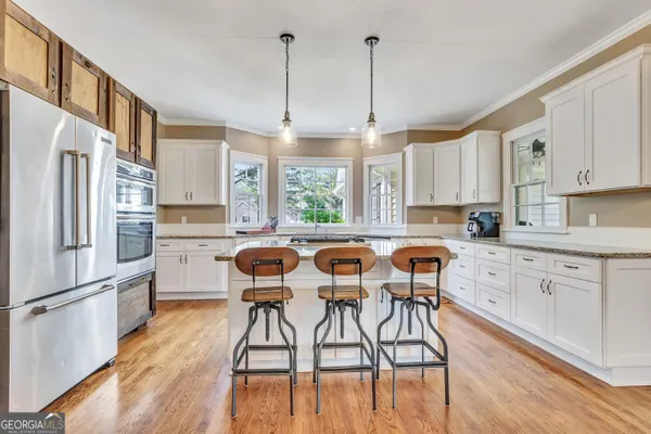 a kitchen with stainless steel appliances granite countertop a stove a sink dishwasher a refrigerator and a dining table with wooden floor