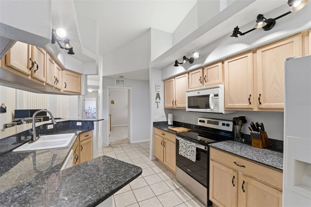 5220 Kirkwood Avenue Spring Hill, FL 34608 - Photo 13 of 67 a kitchen with stainless steel appliances granite countertop a sink a stove a refrigerator cabinets and living room view