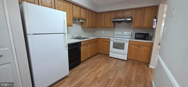 a kitchen with a refrigerator a stove top oven and wooden floor