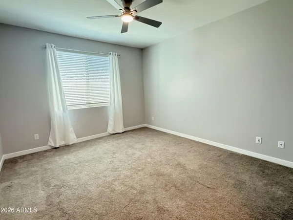an empty room with a chandelier fan and windows