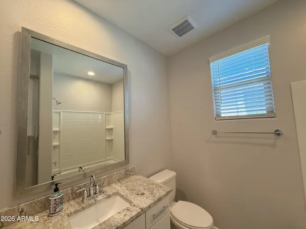 a bathroom with a granite countertop sink toilet and mirror