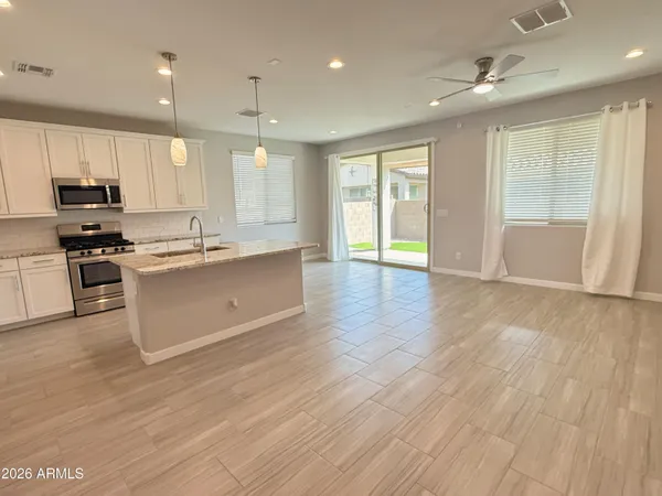 a large kitchen with stainless steel appliances granite countertop a stove a sink dishwasher and a refrigerator with wooden floor