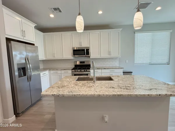 a kitchen with kitchen island granite countertop a refrigerator a sink a stove a microwave and wooden cabinets