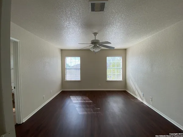 an empty room with wooden floor and windows
