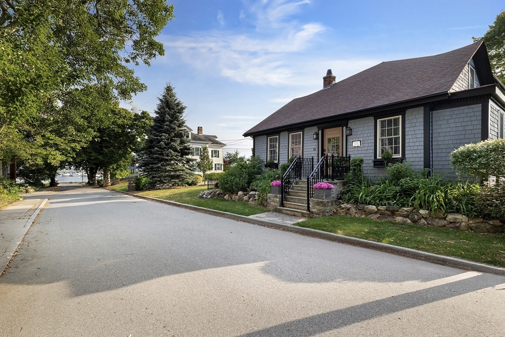 a view of a brick house with a yard and a large tree
