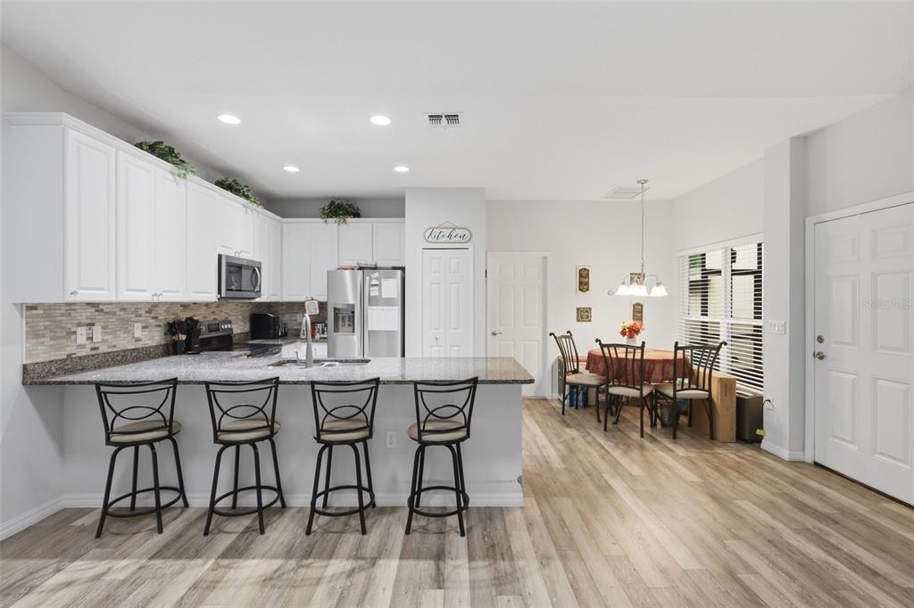 205 Merlot Street DeLand, FL 32724 - Photo 12 of 34 a kitchen with stainless steel appliances granite countertop a dining table chairs stove a refrigerator and cabinets