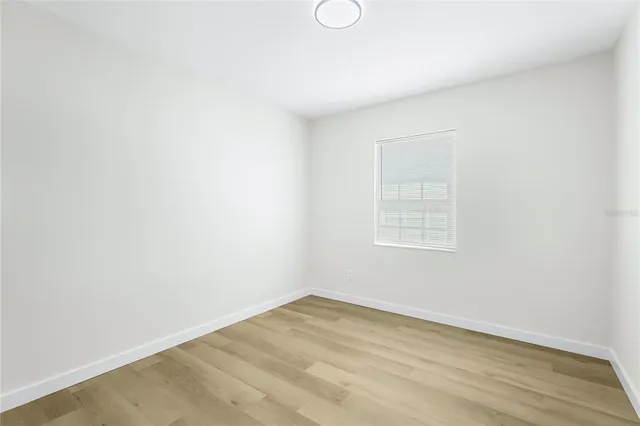 a view of an empty room with wooden floor and windows