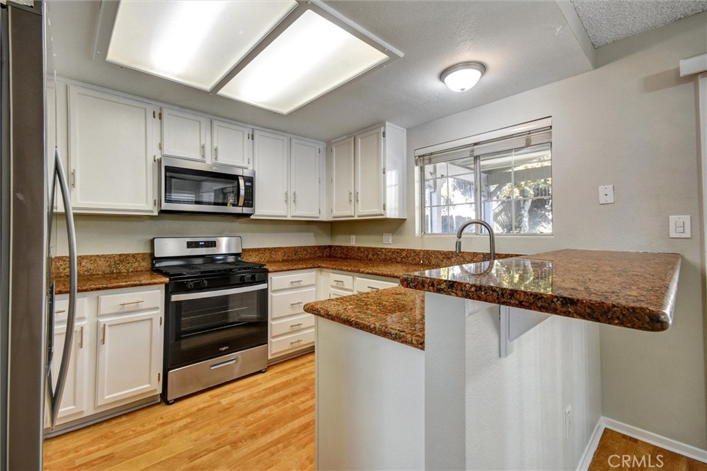 11024 Charleston Street Rancho Cucamonga, CA 91701 - Photo 6 of 30 a kitchen with granite countertop a sink cabinets and stainless steel appliances