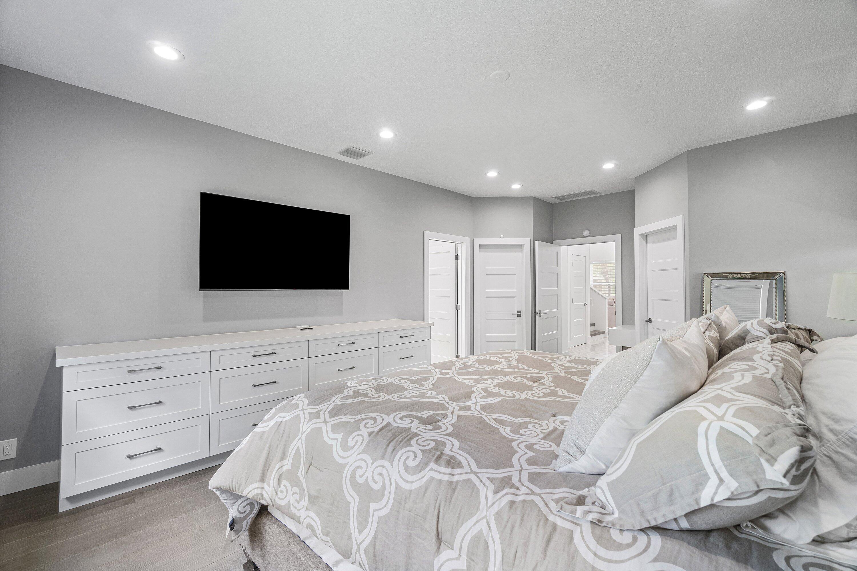 2404 Northwest 67th Street Boca Raton, FL 33496 - Photo 20 of 74 a spacious bedroom with a bed and a flat screen tv in white walls