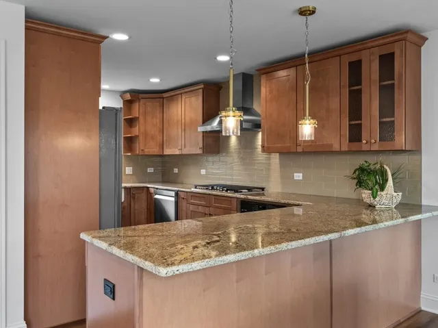 a kitchen with stainless steel appliances granite countertop a sink a stove and a wooden cabinets