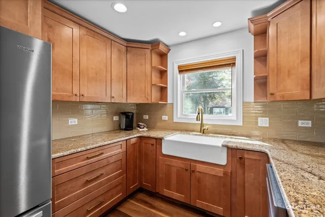 a kitchen with granite countertop stainless steel appliances a sink window and cabinets
