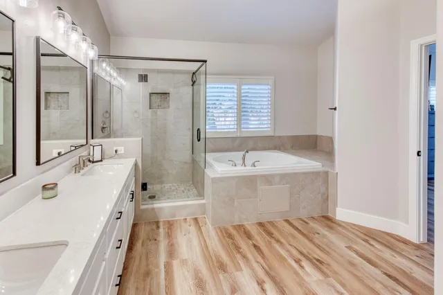 a bathroom with a tub double vanity sink and mirror
