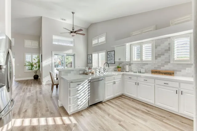 a spacious bathroom with sinks a chandelier and a wooden floor