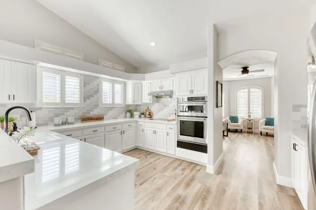 a large white kitchen with a stove a sink dishwasher and a oven with white cabinets