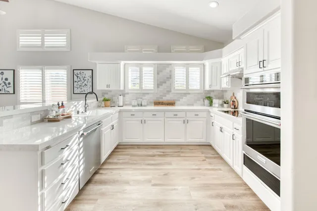 a large white kitchen with stainless steel appliances granite countertop a sink and window