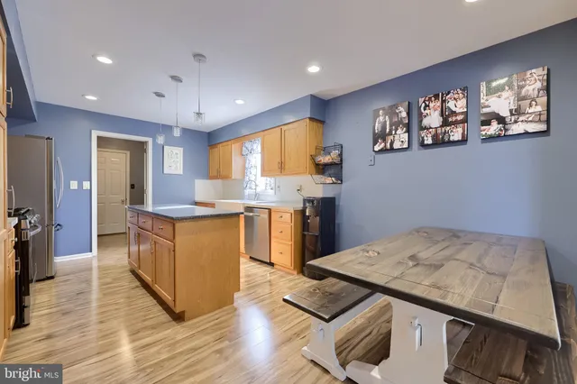 a kitchen with stainless steel appliances granite countertop a stove top oven a refrigerator a sink and dishwasher with wooden floor