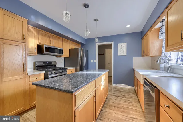 a kitchen with granite countertop a stove a sink a refrigerator and wooden cabinets